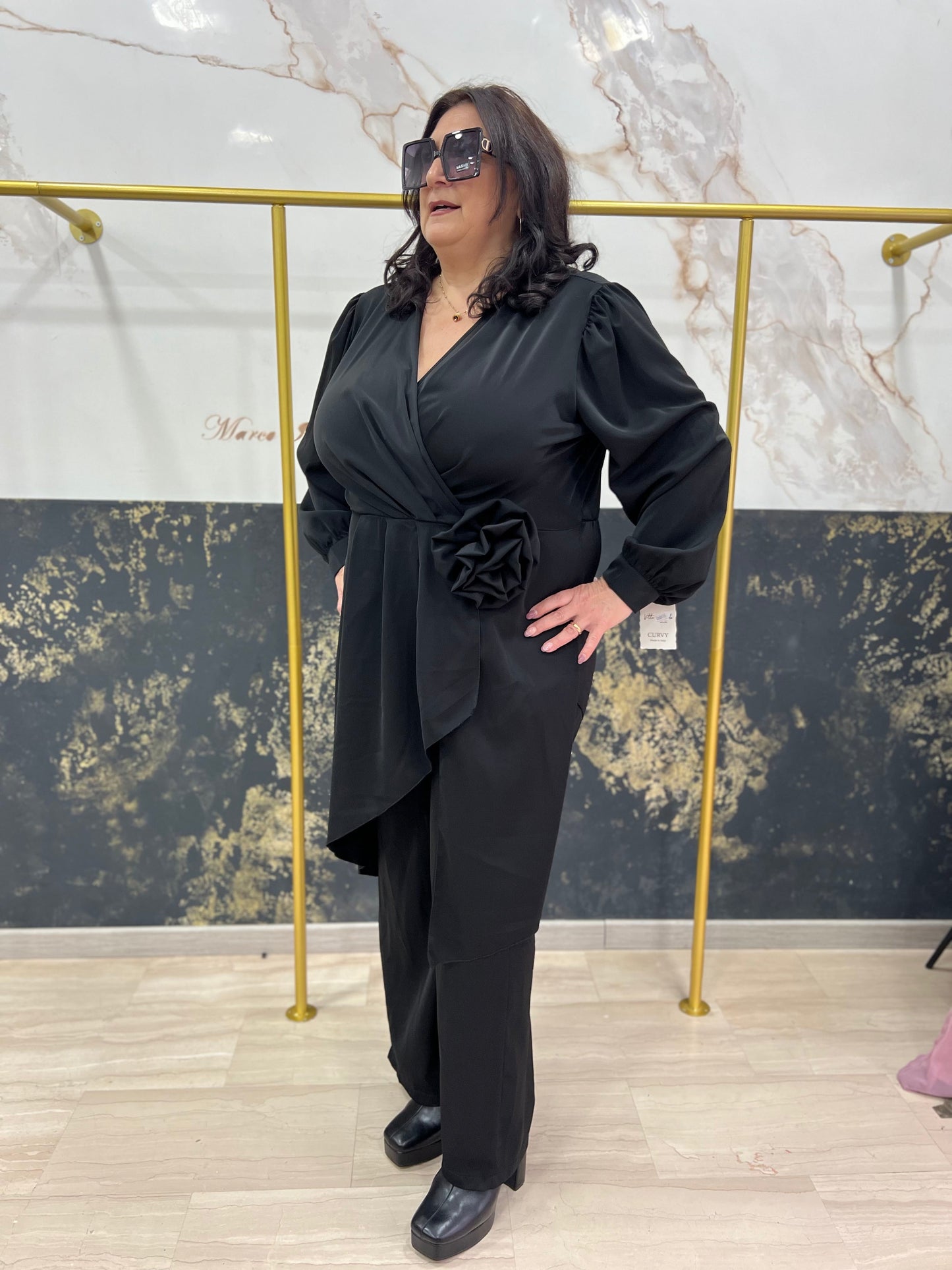 Tuta intera elegante curvy con fiore e casacca asimmetrica – disponibile in nero, prugna e marrone
